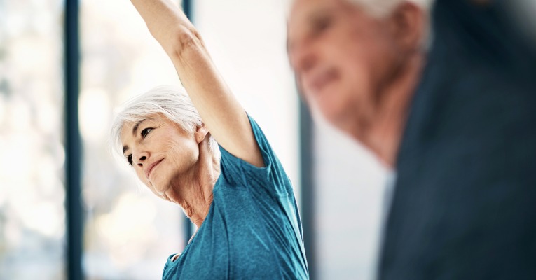 photo d'une femme âgée qui s'étire et pratique la gymnastique ou le yoga et montre à quel point cela est bon pour soulager ses douleurs d'arthrose de genou ou de gonarthrose