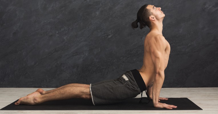 jeun homme de profil pratiquant étirement de yoga dos en extension sur tapis pour douleurs dorsales type dorsalgie