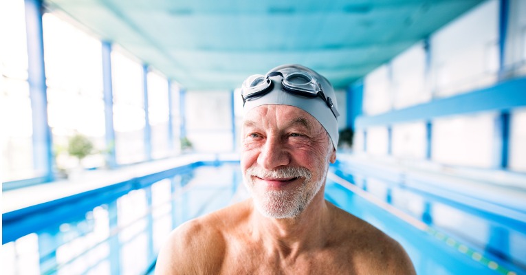 photo d'un sénior avec un bonnet de bain qui sourit après avoir nagé dans une piscine pour se soulager des douleurs d'arthrose de genou et de gonarthrose