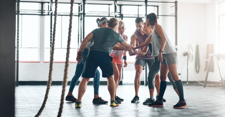 photo d'un groupe de sportifs dans une salle de sport au milieu des accessoires de musculation qui se motivent et s'encouragent mutuellement pour leur séance de musculation 