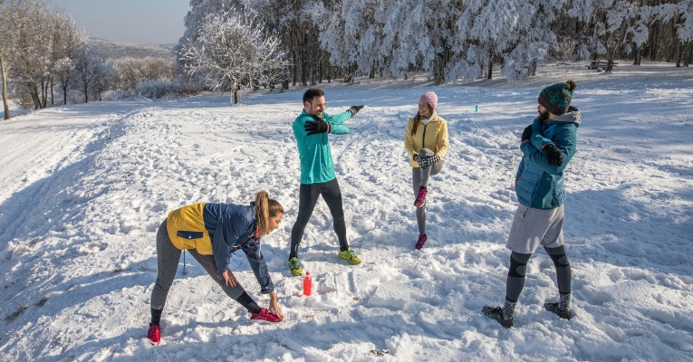 photo d'un groupe de sportif qui s'échauffe les bras et les jambes en plein hiver pour éviter de se blesser ou de se faire un claquage musculaire
