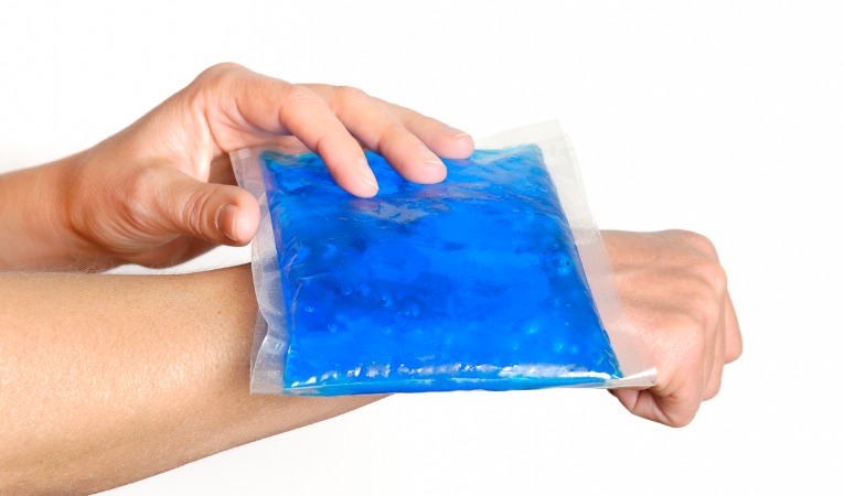 un homme applique un pack de glace pour soulager ses douleurs et faire dégonfler son poignet après une fracture du poignet