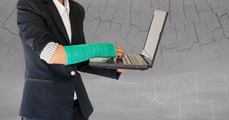 homme qui travail sur son ordinateur avec un plâtre du bras afin de protéger sa fracture du poignet