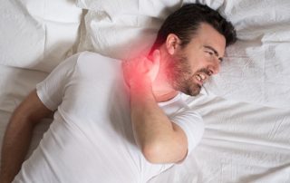 un homme allongé dans son lit qui souffre d'un torticolis au réveil après une mauvaise nuit
