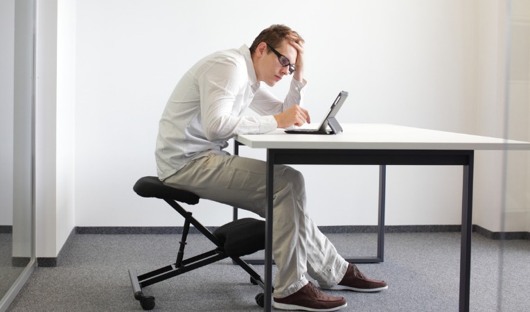homme assis enroulé position avachie mauvaise position et posture de travail avec risque de sciatique