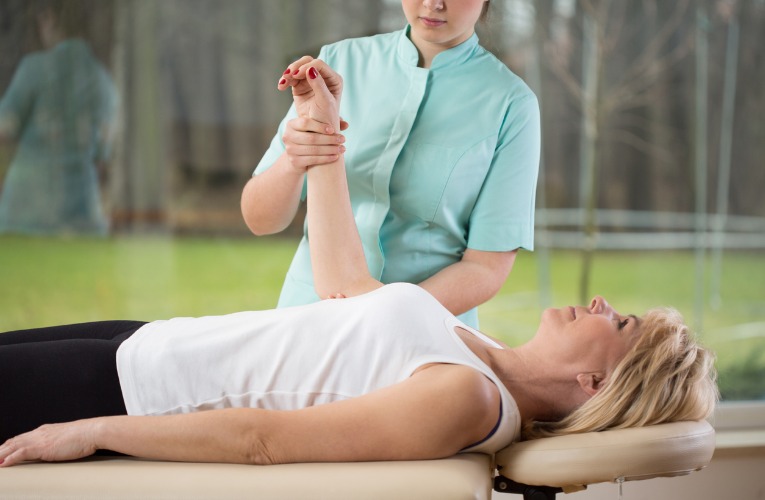 une femme kiné réalise une manipulation du coude lors d'une séance de rééducation et illustre comme la kinésithérapie est indispensable pour soigner correctement une tendinite interne du coude ou golf elbow
