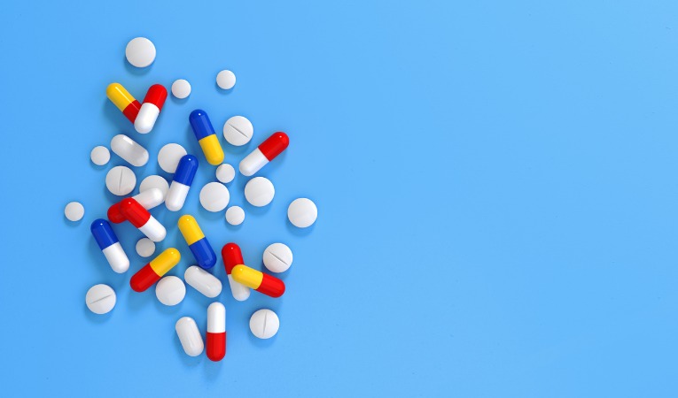 photo sur fond bleu d'un mélange de pilules et médicaments anti douleur utilisé pour soulager le lumbago 