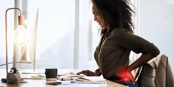 photo d'une jeune femme qui souffre du bas du dos à cause d'un lumbago en télétravail.